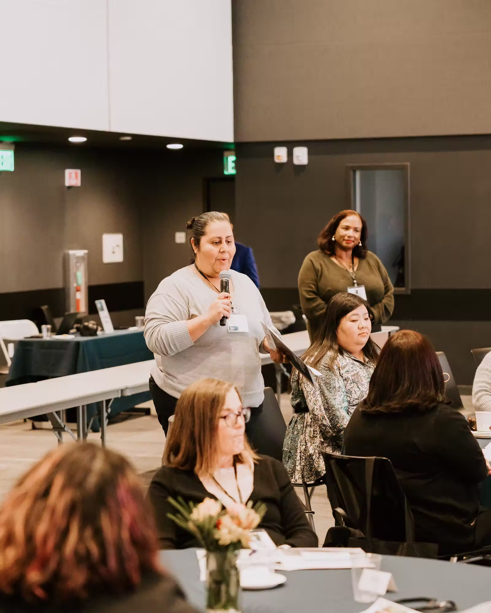 A woman addresses an audience at a conference, engaging with attendees through her speech and presentation.